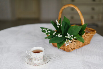 lilies of the valley in the basket and a cup of tea