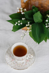lilies of the valley in the basket and a cup of tea