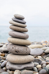 Pyramid of sea stones on the seashore at the pebble beach. Concept of harmony and balance.