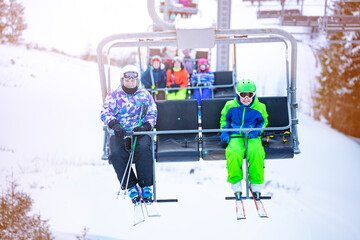 Boy and girl sit on the ski chair lift together on Alpine mountain resort view from another seat