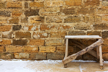 Construction site for repair, winter, table for plastering and molar works on the background wall of a building made of natural stone