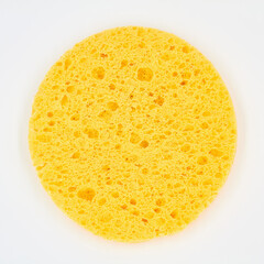 A round yellow cosmetic sponge pad for face make-up cleaning on white background