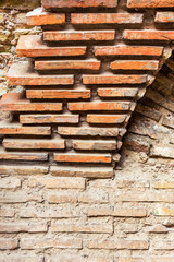 Collapsing stone wall of an old house with brick masonry