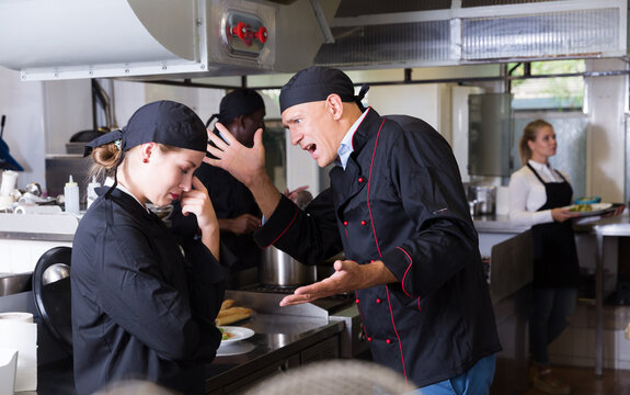 Angry chef talking to female assistant