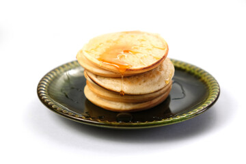 On a white isolated background pancakes on a green plate. Close up side view.
