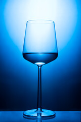 Transparent wine glass filled with water on a blue and white background.