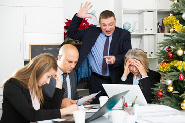 Outraged businessman expressing dissatisfaction with work of frustrated team during annual report...
