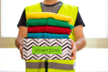 Volunteer with vest taking a box with donated clothes. Volunteer and donated clothing concept....