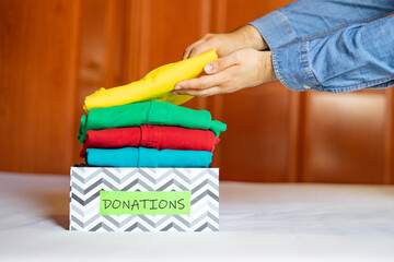 Man putting donated clothes in a box. Concept of donating clothes. Donations and charity.