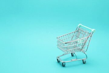 Miniature empty shopping cart on colorful background