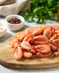 Prawns on a wooden Board on the light gray kitchen table. Lots of prawns on the serving board