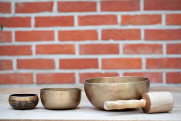 Ancient hand crafted traditional Tibetan meditation and healing singing bowls made from 7 sacred metals which are typical accessories used in buddhism, yoga and meditation, against a red brick wall