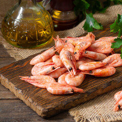 Shrimp on a wooden Board on a brown wooden table. Lots of prawns on the serving Board. Prawns close up