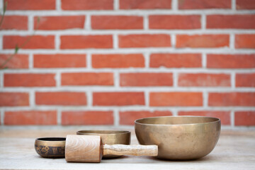 Ancient hand crafted traditional Tibetan meditation and healing singing bowls made from 7 sacred metals which are typical accessories used in buddhism, yoga and meditation, against a red brick wall