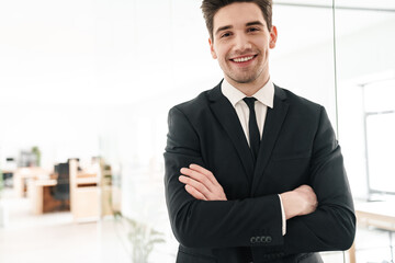 Image of happy businessman smiling while standing with hands crossed