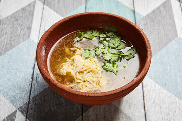 Classic chicken broth in brown pottery bowl