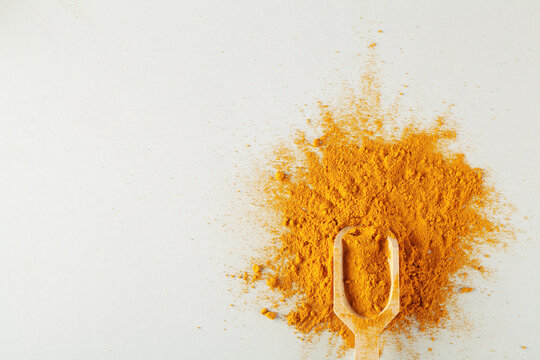 Turmeric Powder In Wood Spoon On Gray Background