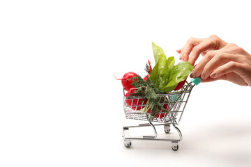 Hand pushing small shopping cart full with vegetables isolated on white background