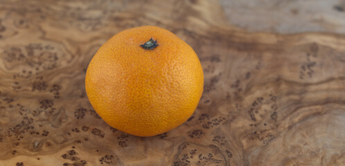 Whole Satsuma Mandarine on a wooden board with an intricate pattern