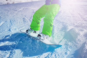 Close up of the snowboard of the boy in motion going down the slope on the mountain ski resort