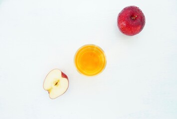 Apple juice in a glass and ripe fruit on a cream-colored table