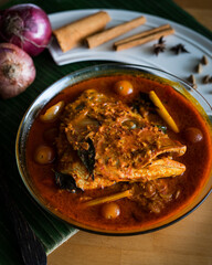Malaysian traditional dish, fish head curry served on banana leaf with various ingredients spices . Selective focus.