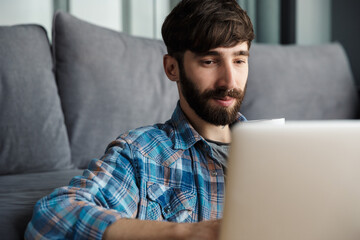 Image of thinking man working with notebook while sitting on floor