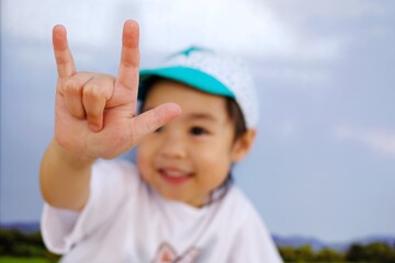 An adorable little asian girl show her hand, the sign hand language "I love you". Blured of her face, focus at her finger.