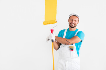 Friendly worker painting wall with yellow paint