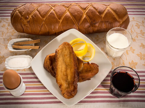 barra de pan de torrijas tradicional con decoraci&oacute;n de canela lim&oacute;n leche vino sobre mantel de rayas