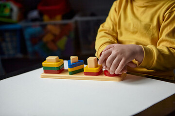 The boy is playing in his room. Educational game. Learning shapes and colors. A child plays with a sorter.