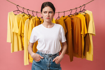 Photo of young sad woman posing at camera with hands in pockets