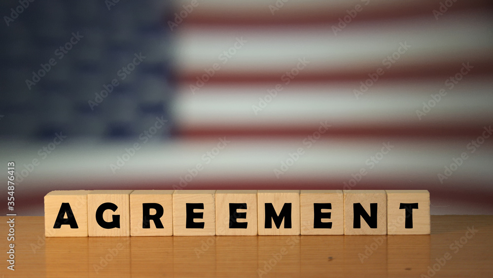 Poster agreement message word on a wooden desk on cube blocks with a usa flag background.