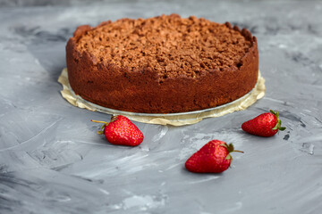 Chocolate cake is decorated with strawberry berries. Homemade cake. Pie on a grey background