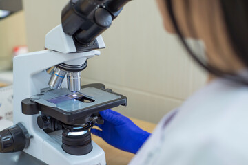 laboratory assistant is looking through a microscope. Close-up doctor laboratory assistant looking...