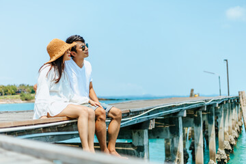 Honeymoon travel couple romantic  hugging and sitting on wood bridge and enjoys their tropical holiday.