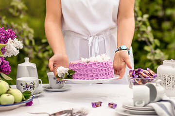 Obraz na płótnie Canvas woman puts lilac cake on the table