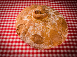 hogaza  de Pan payes redondo boina  tradicional artesano de tahona sobre mantel de cuadros 