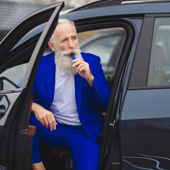 Old stylish man in car sales center. Mature man choosing new automobile.