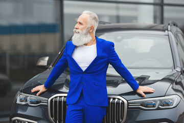 Old stylish man in car sales center. Mature man choosing new automobile.