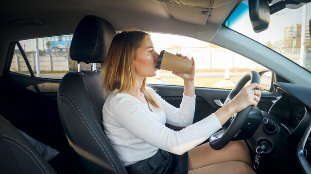 Beautiful Blonde Woman Drinking Coffee In Car While Commuting To Work