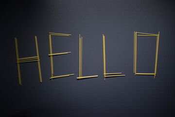 Word 'HELLO' written with spaghetti on gray background, top view, copy space. Food supplies, food donation on quarantine while coronavirus.