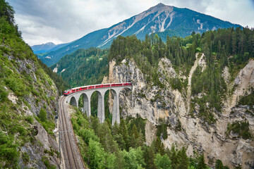 Roter Zug fährt über die Brücke des Landwasserviadukts im Kanton Graubünden, Schweiz. Bernina Express / Glacier Express nutzt diese Bahn.