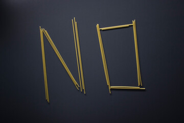 Word 'NO' written with spaghetti on gray background, top view, copy space. Food supplies, food donation on quarantine while coronavirus.