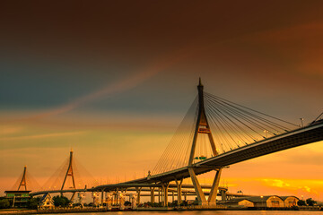 Naklejka na ściany i meble The blurred background of the twilight evening by the river, the natural color changes, the bridge over the river (Bhumibol Bridge) is one of the major transportation bridges in Bangkok, Thailand