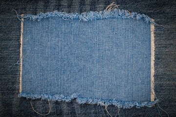 Destroyed torn denim blue jeans fabric frame on blue jeans background. 