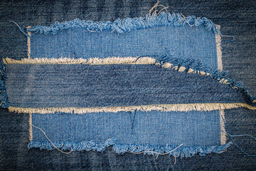 Destroyed torn denim blue jeans fabric frame on blue jeans background. Worn Jeans Casual Double Color patch Denim. - obrazy, fototapety, plakaty