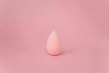 Pink beauty blender isolated on pink background with copy space. Pink blending sponge for makeup....