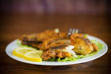 fried hake fish in batter with lettuce and lemon in a plate