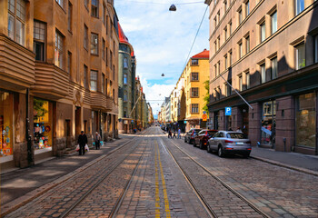 Fototapeta na wymiar street with cars, people, colorful old buildings and architecture and cloudy blue sky in Helsinki, Finland